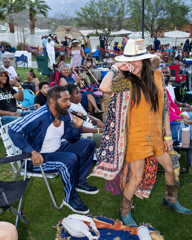 A crowd of Pip's Lifestyle members enjoying an afternoon set on the lawn, one guest laughing in a wide-brimmed hat