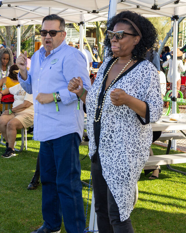 Two members up on their feet dancing to the band under the tent